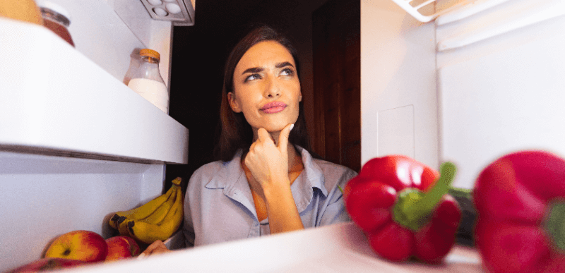 冷蔵庫を見て考える女性