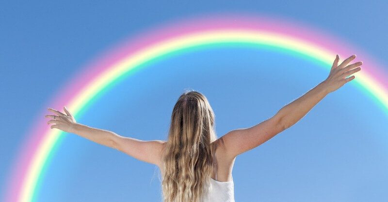 虹を前に手を広げる女性